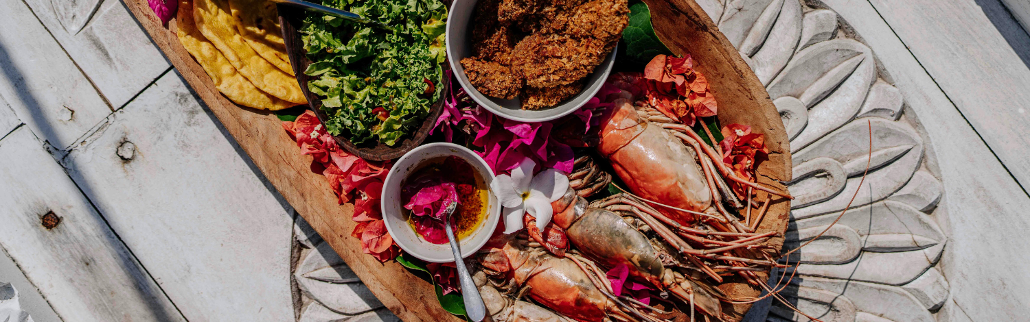A wooden tray filled with shrimp, assorted vegetables, and various other dishes arranged appetizingly