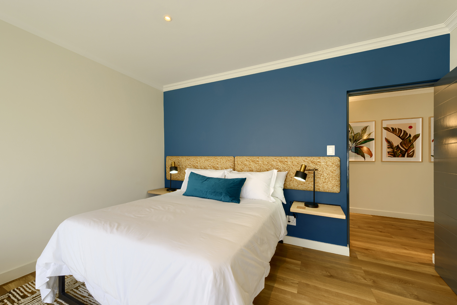 A neatly made bed with white linens in a cozy, softly lit bedroom.