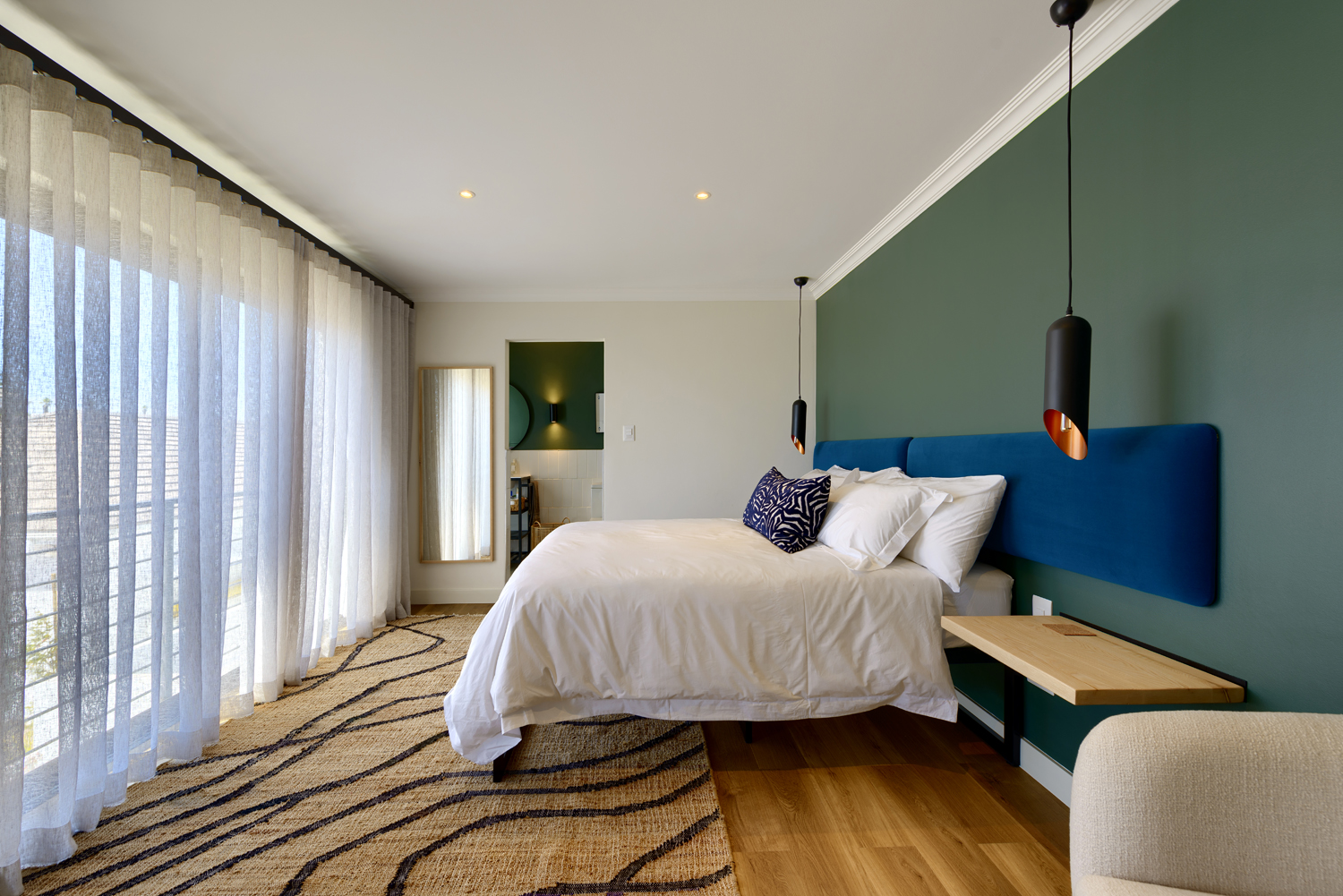 A neatly made bed with white linens in a cozy, softly lit bedroom.